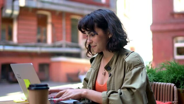 Caucasian freelancer making online webinar translation during remote working in street cafe, skilled female graphic designer with laptop computer communicate during video calling on netbook
