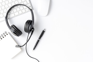 Helpdesk desktop with headset, computer and accessories. White background with copyspace