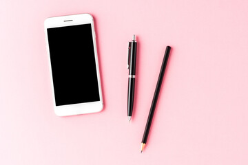 Smart phone with empty screen and pens on pink table. Business background