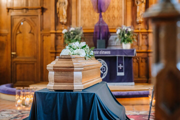 A coffin decorated with many flowers and candles in a beautiful church, ceremony