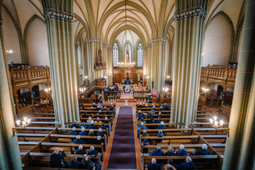 People sit in a church at a funeral, with the coffin in the middle by the altar