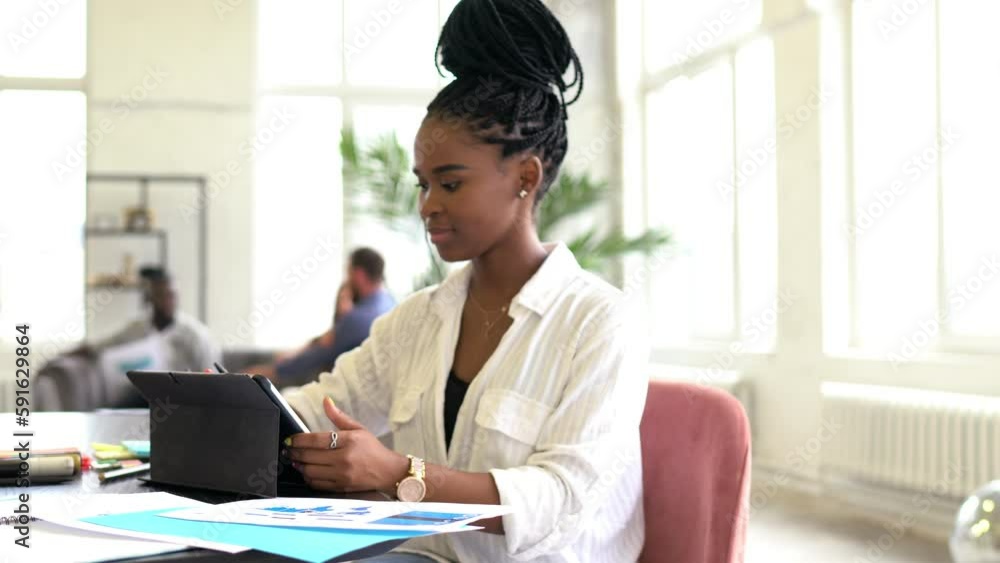 Poster african american female freelancer checking information on documents and using digital tablet for cr