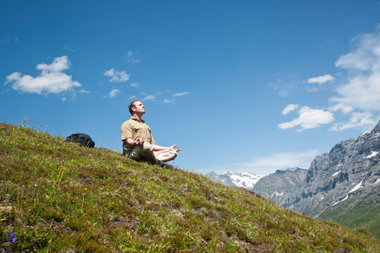 Man Sitting on Mountain Side, Meditating, Bernese Oberland, Switzerland