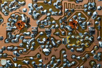 A part of a printed circuit computer board with tracks. PCB without radio components. Old printed circuit board background with soldering trace, closeup, top view