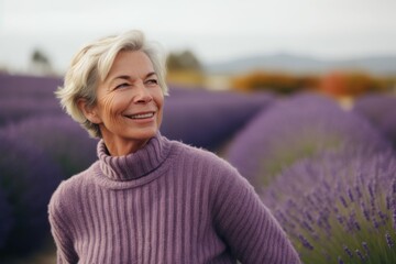 Portrait of happy senior woman standing in lavender field and smiling