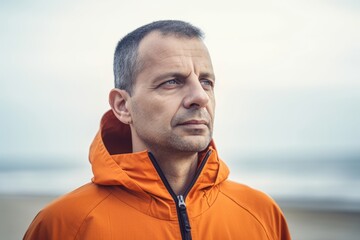 Portrait of a man in an orange jacket on the beach.