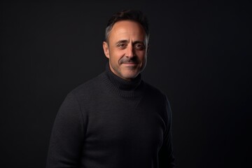 Fototapeta premium Portrait of a middle-aged man in a black sweater on a black background.