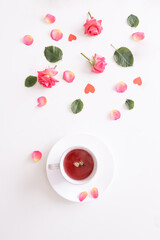 Fototapeta na wymiar Cup of tea with pink rose on white background. Top view. Copy space. 