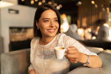 Young smiling woman drinking coffee in hotel restaurant