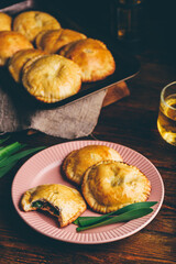 Freshly Baked Hand Pies Filled with Chives and Mushrooms. One Pie with Bite Taken Out of It