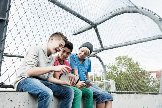 Three Boys Playing Video Games in Playground, Mannheim, Baden-Wurttemberg, Germany