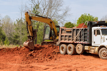 Earth is being loaded into dumper truck by an excavator