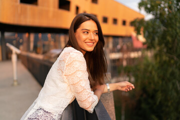 Young laughing charming woman portrait in the city at sunset
