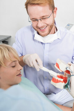 Dentist demonstrating to Boy how to Brush Teeth during Appointment, Germany