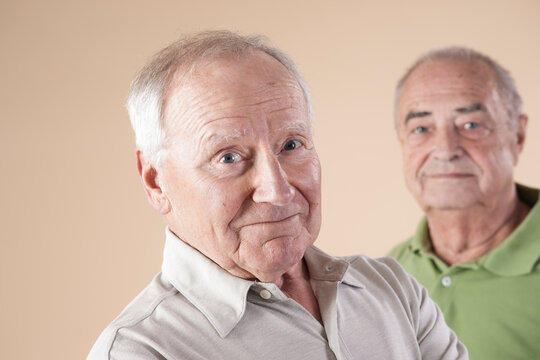 Portrait of Two Senior Men Looking at Camera, Studio Shot on Beige Background
