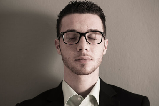 Close-up Portrait of Young Man wearing Glasses with Eyes Closed, Studio Shot