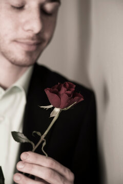 Close-up Portrait of Young Man holding Red Rose with Eyes Closed, Studio Shot