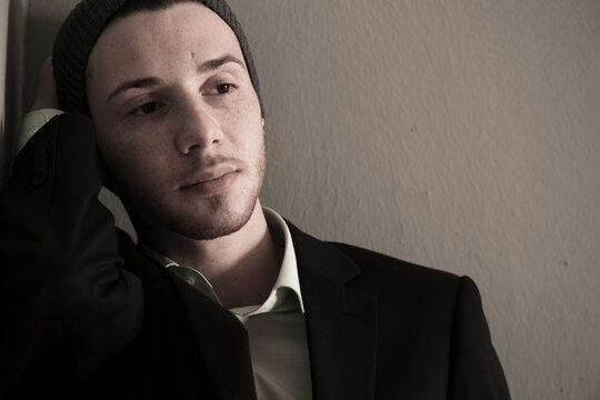 Portrait of Young Man wearing Woolen Hat and Suit Jacket, Looking to the Side, Absorbed in Thought, Studio Shot