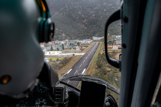 Famous Lukla airport with its inclined airstrip seen from the perspective of helicopter pilot during landing