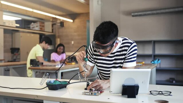 Latin teenage student learning to solder electronics circuit in the engineering technology course 