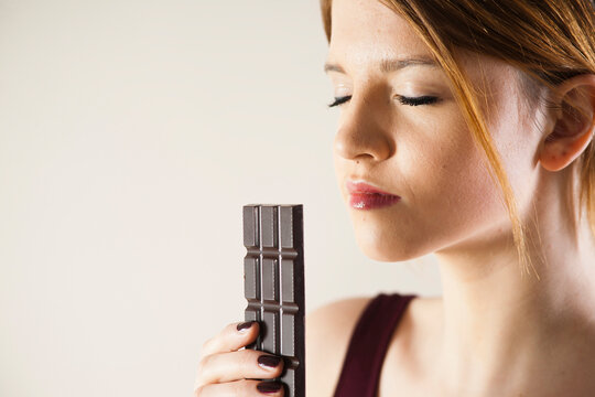 Teenage Girl holding Chocolate with Eyes Closed, Studio Shot on White Background