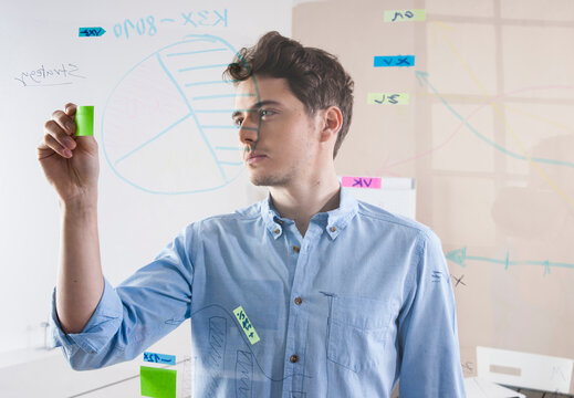 Young Man Working in an Office, Looking Through Glass Board, Germany