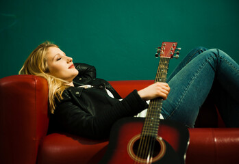 Woman Lying on Sofa and Holding Acoustic Guitar
