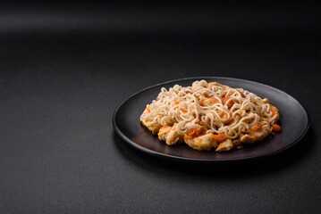 Obraz na płótnie Canvas Delicious noodles with chicken and vegetables or udon on a black ceramic plate