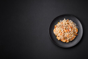 Delicious noodles with chicken and vegetables or udon on a black ceramic plate