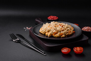 Delicious noodles with chicken and vegetables or udon on a black ceramic plate