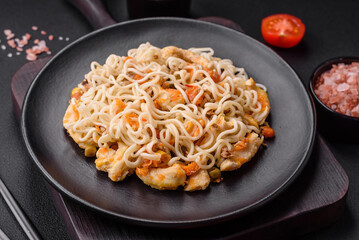 Delicious noodles with chicken and vegetables or udon on a black ceramic plate