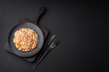 Delicious noodles with chicken and vegetables or udon on a black ceramic plate