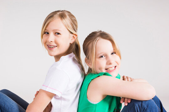 Portrait of Girls Sitting Back to Back in Studio
