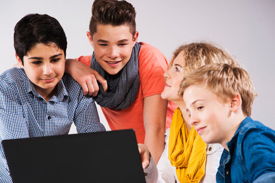 Teenagers Looking at Laptop Computer, Studio Shot