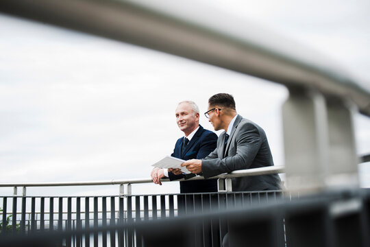 Mature businessmen standing on bridge talking, Mannheim, Germany