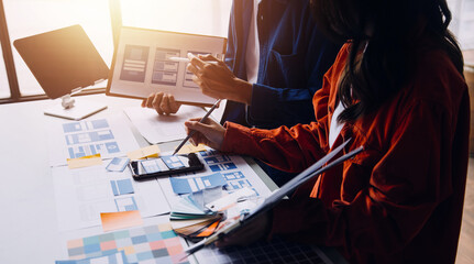 Close up ux developer and ui designer brainstorming about mobile app interface wireframe design on table with customer breif and color code at modern office.Creative digital development agency