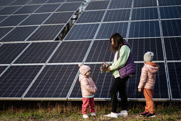 Mother with two daughters on the background of solar panels.  Eco energy.
