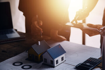 Three colleagues discussing data working and tablet, laptop with on on architectural project at construction site at desk in office