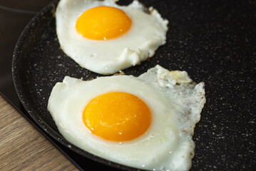 Frying eggs in a frying pan on electric stove