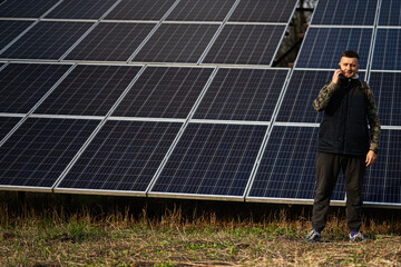 Man with mobile phone on the background of solar panels.  Eco energy.