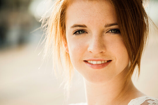 Close-up portrait of teenage girl outdoors, smiling at camera