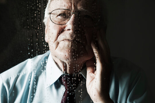 Elderly Man Looking out Window on Rainy Day