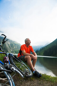 Mature Man Sitting by Lake with Mountain Bike, Vilsalpsee, Tannheim Valley, Tyrol, Austria