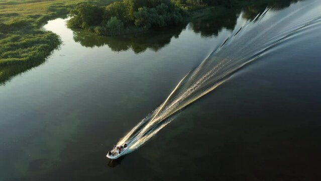 Aerial view to motorboat on calm water at morning light