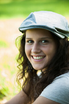 Close-up portrait of teenaged girl wearing cap outdoors, smiling and looking at camera, Germany