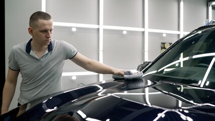 The worker wipes the car with a rag. Car service worker applying nano coating on a car detail. Car...