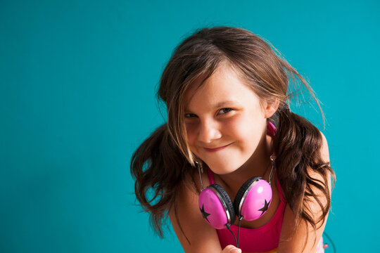 Portrait of girl wearing headphones around neck, looking at camera, making funny faces, Germany