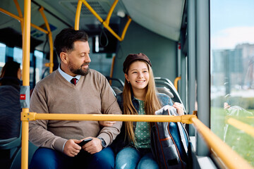 Happy father and daughter riding in public bus.