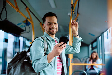 Young man using mobile phone while commuting by public transport. - obrazy, fototapety, plakaty