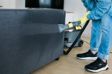 Man in protective rubber glove cleaning sofa with professionally extraction method with washing...